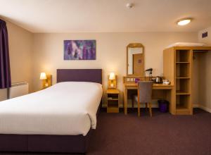 a hotel room with a bed and a desk and a bed and a mirror at Middleton Inn, Manchester in Manchester