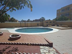 a large swimming pool in a patio with a tree at Apartamento LOLO in El Médano