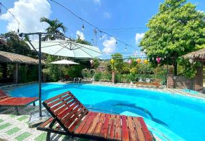 a swimming pool with a bench and an umbrella at Tam Coc Riverside Bungalow in Ninh Binh