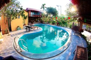 a large swimming pool in a yard with benches around it at Tam Coc Riverside Bungalow in Ninh Binh