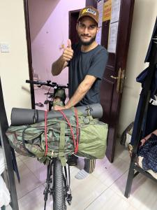 a man giving a thumbs up next to a bike at Turkish beach hostel in Muscat