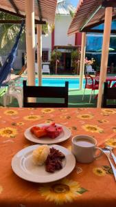 a table with two plates of food and a cup of coffee at Pousada Mar dos Sonhos in Paripueira