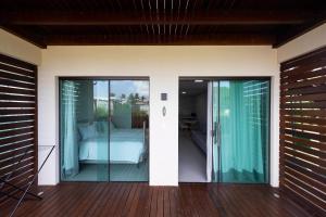 a room with glass doors and a bed on a deck at Flats do Cuca in Fernando de Noronha
