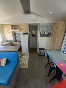 a small kitchen with a blue couch and a table at Mobil Home Sainte Baume 6 personnes in Nans-les-Pins