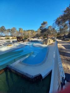 a swimming pool with blue water and a bridge at Mobil Home Sainte Baume 6 personnes in Nans-les-Pins