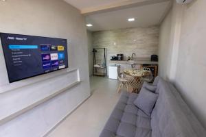 a living room with a couch and a tv on a wall at Flats do Cuca in Fernando de Noronha