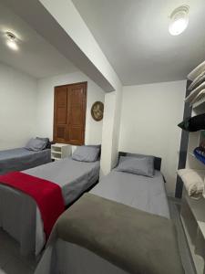 a bedroom with two beds and a clock on the wall at Quartos Confortáveis em Belo Horizonte in Belo Horizonte