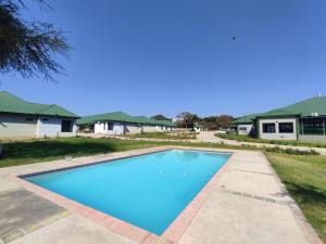 a blue swimming pool in front of a house at GreenLand Hotel in Kasane