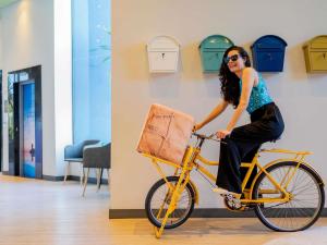 a woman riding a yellow bike with a purse at ibis Styles Sorocaba Santa Rosalia in Sorocaba
