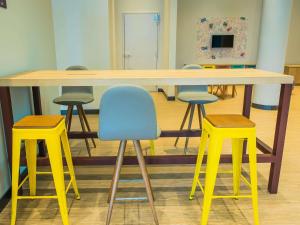 a large table with four yellow stools in a room at ibis Styles Sorocaba Santa Rosalia in Sorocaba
