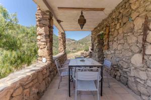 a stone walled patio with a table and chairs at Casa Lucía - Off grid vakantiehuisje - Puerto Mika in Torviscón