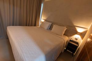 a bedroom with a large white bed with two pillows at Flats do Cuca in Fernando de Noronha +4 photos
