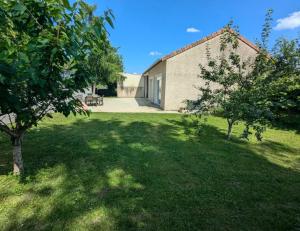 a green yard with trees and a building at Dépendance au goût de vacances in Moulainville-la-Basse