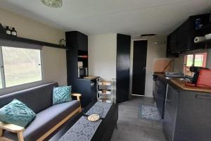 a living room with a couch and a kitchen at Le Chalet du Lâcher-Prise in Éguzon-Chantôme
