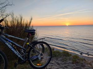 a bike parked on the beach at sunset at Róża Wiatrów Leśny Klif in Debina +8 photos