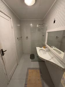 a bathroom with a sink and a shower and a mirror at Quartos Confortáveis em Belo Horizonte in Belo Horizonte