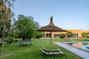 a patio umbrella and chairs next to a pool at Domaine Bahi - Marrakech in Marrakesh