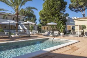 a pool with chairs and umbrellas next to a building at Valentin Somni Hotel & Suites in Paguera