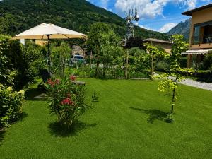 a lawn with an umbrella and flowers and a house at Il Giardino di Lilly with private parking garden and air conditioning in Porlezza