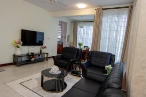 a living room with leather furniture and a flat screen tv at JJC BNB Mbweni in Bunju
