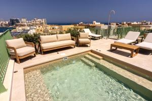 a hot tub on a patio with chairs and a view at The Vincent Boutique Hotel, BW Premier Collection in Valletta