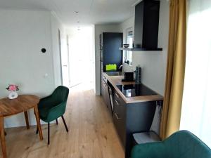 a kitchen with a table and a green chair at OV815- Chalet Eveline in Blokzijl