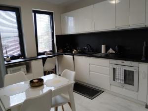 a kitchen with white cabinets and a table and chairs at Апартамент ДОРА in Kazanlŭk +22 photos