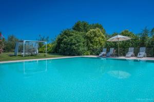 a swimming pool with chairs and an umbrella at Preseglie Lake Garda in Desenzano del Garda