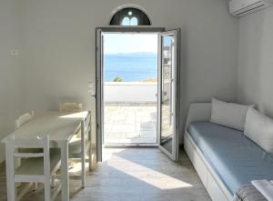 a room with a bed and a table and a mirror at Rosalie Home - Open Sea Studio in Tinos