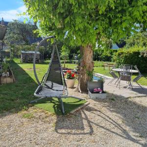 a swing set sitting under a tree in a park at pastelle entre zoo et chateau in Contres
