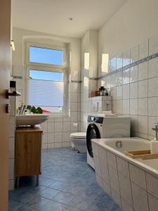 a bathroom with a tub and a toilet and a sink at Stilvolles Apartment Eigenständiger Check-in in Dessau +18 photos