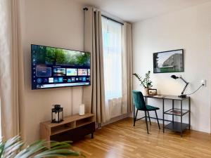 a living room with a desk and a television on the wall at Stilvolles Apartment Eigenständiger Check-in in Dessau