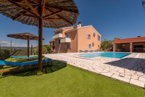 an image of a villa with a swimming pool and umbrellas at Villa Ivana holiday home in Mrljane