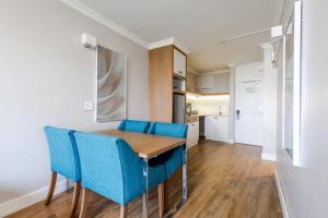a dining room with a wooden table and blue chairs at Breakers Resort 316 Umhlanga in Durban