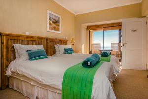 a bedroom with two beds with green and white at Whale Waters Self Catering Gansbaai in De Kelders +23 photos