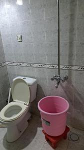 a bathroom with a toilet and a pink bucket at ButtLodges - 1 in Islamabad