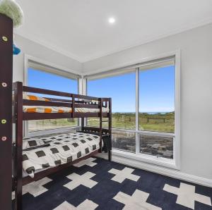 a bedroom with a bunk bed and a large window at Luxurious Home on the Beachside in Port MacDonnell