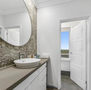 a white bathroom with a sink and a mirror at Luxurious Home on the Beachside in Port MacDonnell