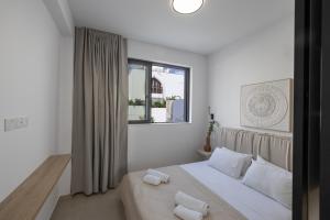 a white bedroom with a bed and a window at Ocean Whispers Villas in Paralimni +62 photos