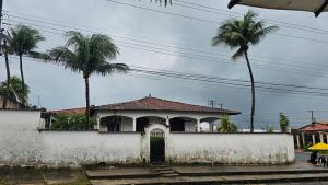 a white house with a gate and palm trees at Casa em Salinas in Salinópolis