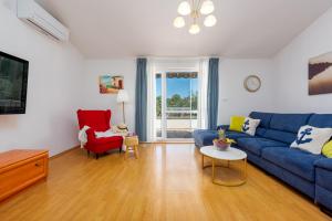 a living room with a blue couch and a red chair at Villa Ivana holiday home in Mrljane