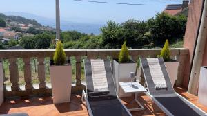 a balcony with two chairs and potted plants at Jo's Studio Flat Limens in Cangas de Morrazo