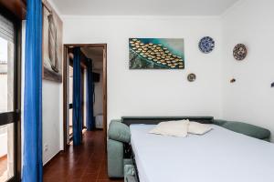 a bedroom with a white bed and a blue couch at Apartamento Vargas in Monte Gordo