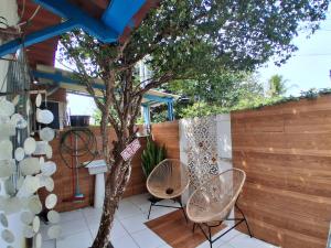 a patio with two chairs and a tree at Santa Monica Beach Tiny House in Guarapari