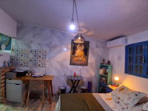 a room with a bed and a table and a painting at Santa Monica Beach Tiny House in Guarapari