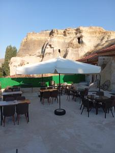 a patio with tables and chairs and an umbrella at Masal Cave Suites - Where Story Begins in Ürgüp