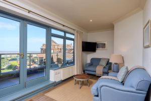 a living room with two blue chairs and a large window at Old Hunstanton Le Strange Arms Hotel in Hunstanton