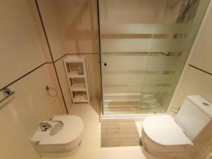 a small bathroom with a toilet and a shower at Apartamento Playa Foz in Foz +26 photos