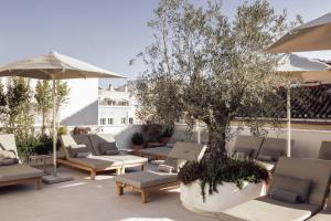 a patio with chairs and a tree and an umbrella at Hotel Well and Come Málaga in Málaga