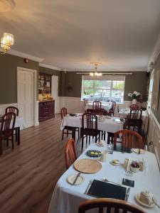 a restaurant with white tables and chairs and a kitchen at Shannonside House N37HF67 in Athlone